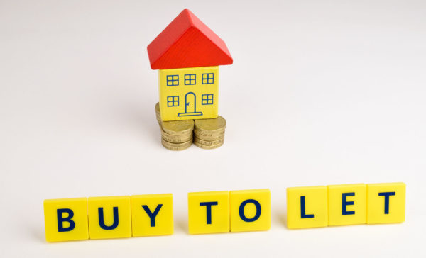 A toy house sitting on a stack of coins with the words, 'Buy To Let' in front of it.